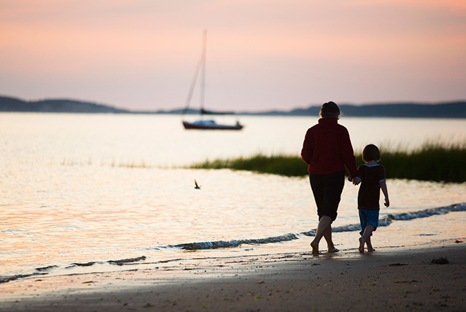 Mother and child walking on the beach.